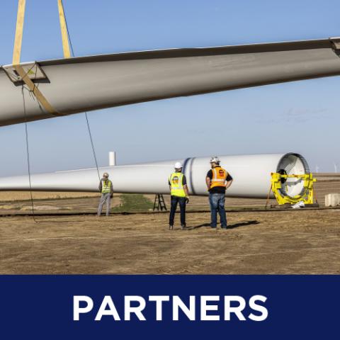 Partners (Workers conversing underneath a windmill blade installation)