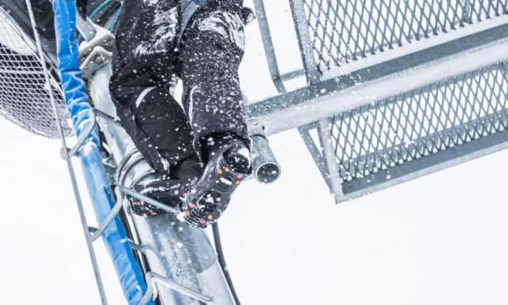 Worker climbing a slippery latter with ice traction on their shoes