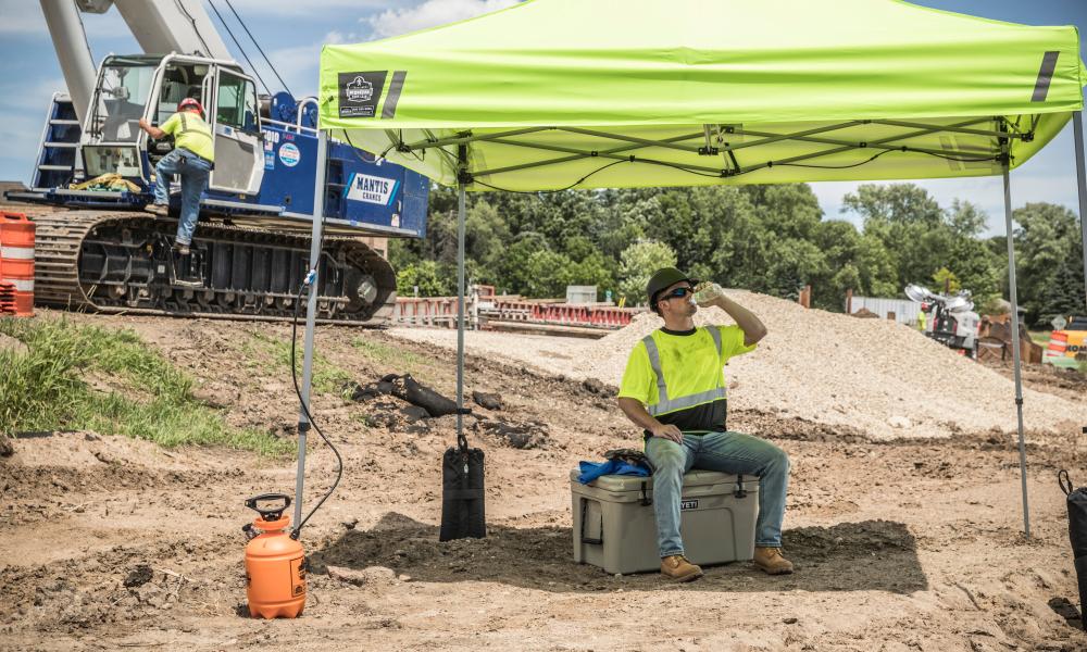 Worker drinking water under tent