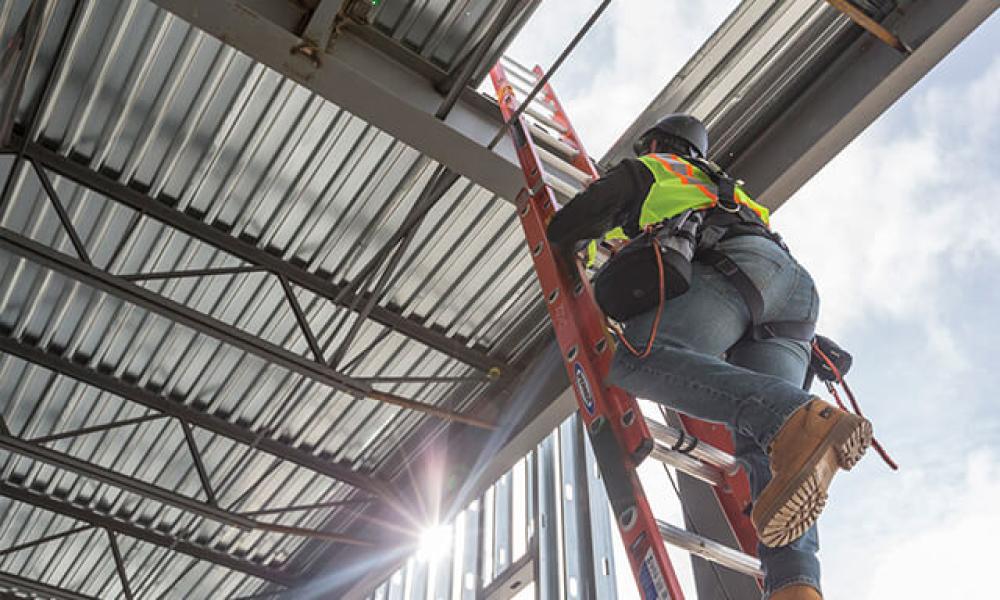 Laborer climbing a ladder to the roof