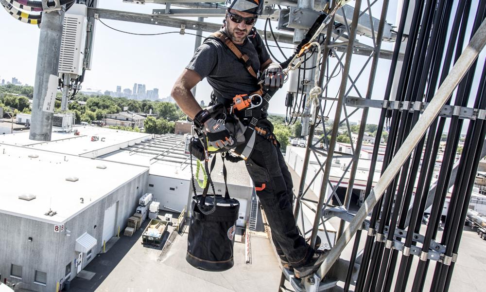 Worker climbing tower with hoist bucket